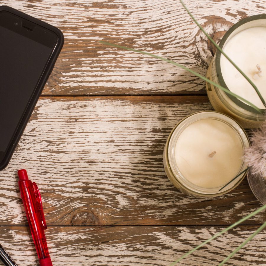 Ein Smartphone liegt auf einem Holztisch neben Deko
