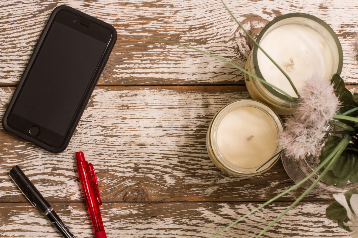 Ein Smartphone liegt auf einem Holztisch neben Deko