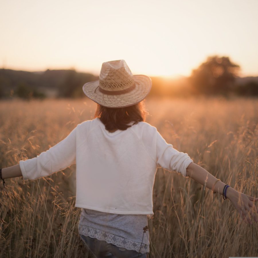 Eine Frau in der Natur mit ausgebreiteten Armen im Sonnenuntergang