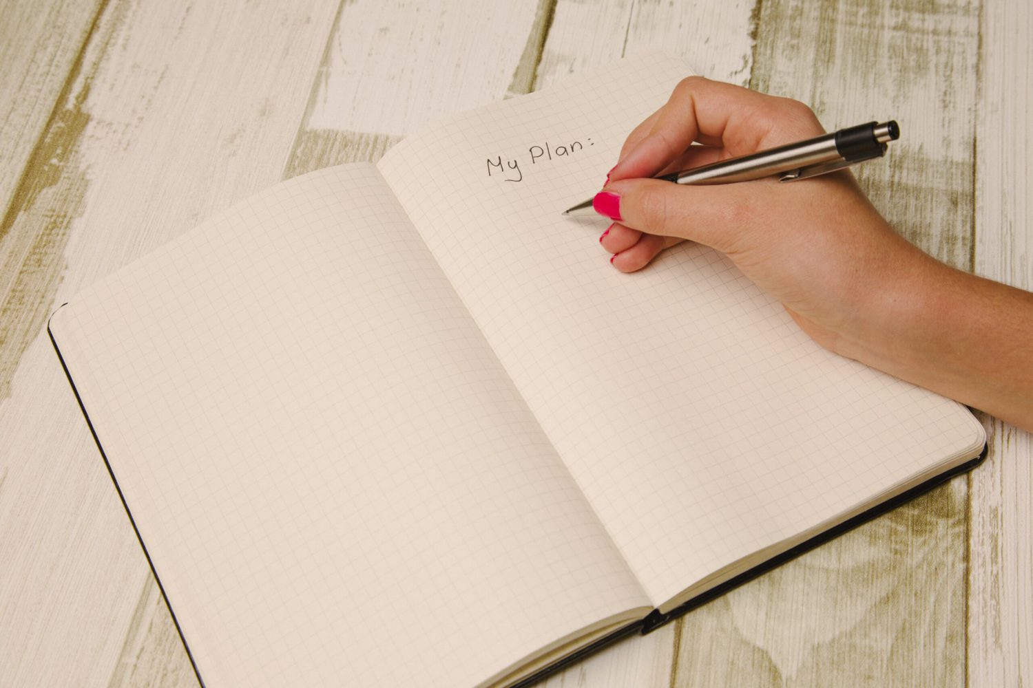 Eine Hand schreibt mit einem Stift auf Papier eine To-Do-Liste